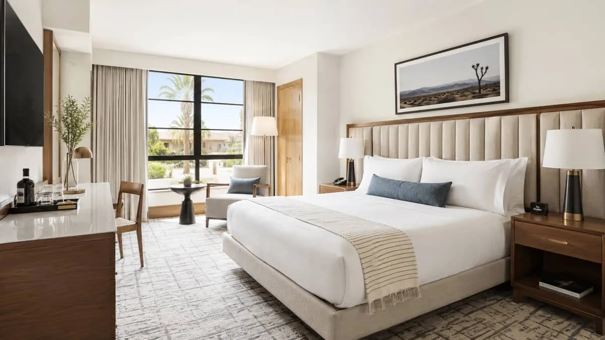 a well-designed boutique hotel guestroom showing a mix of furniture pieces, including an upholstered headboard, wooden n