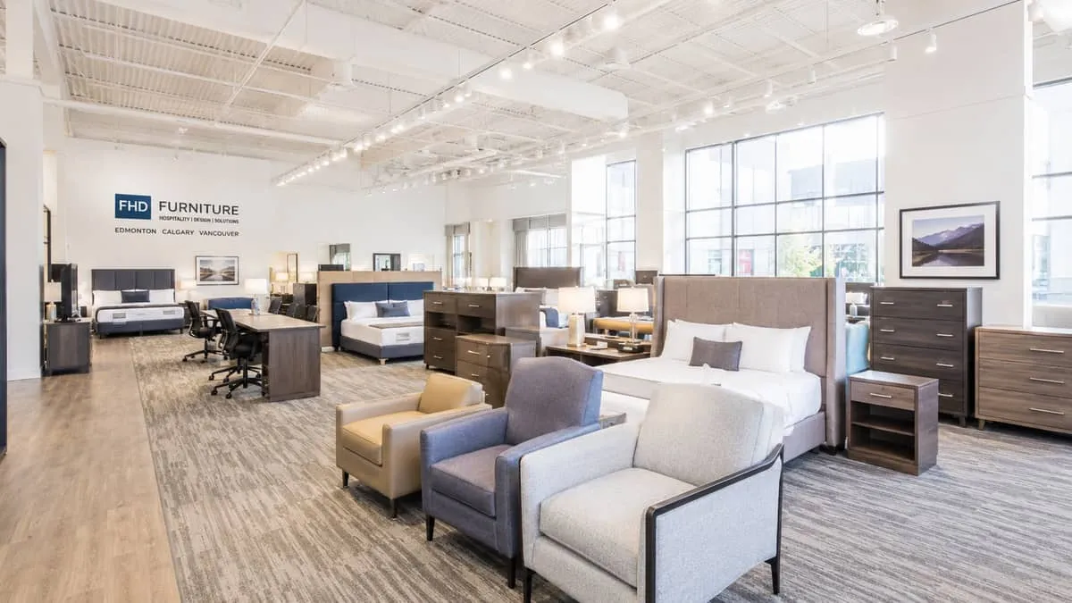 a contract furniture showroom interior with rows of hotel-grade chairs, bed frames, and case goods displayed in a clean,