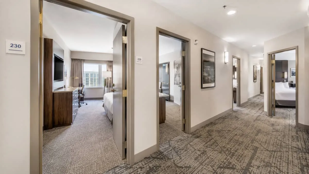 a hotel corridor with matching case goods visible through open room doors, showing consistent furniture placement across