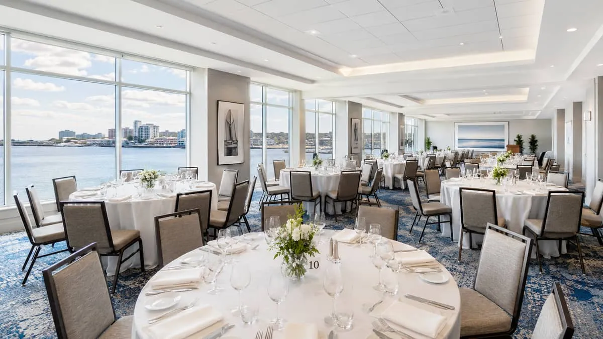 a Halifax waterfront hotel banquet room set for a large corporate dinner, showing round banquet tables with padded chair