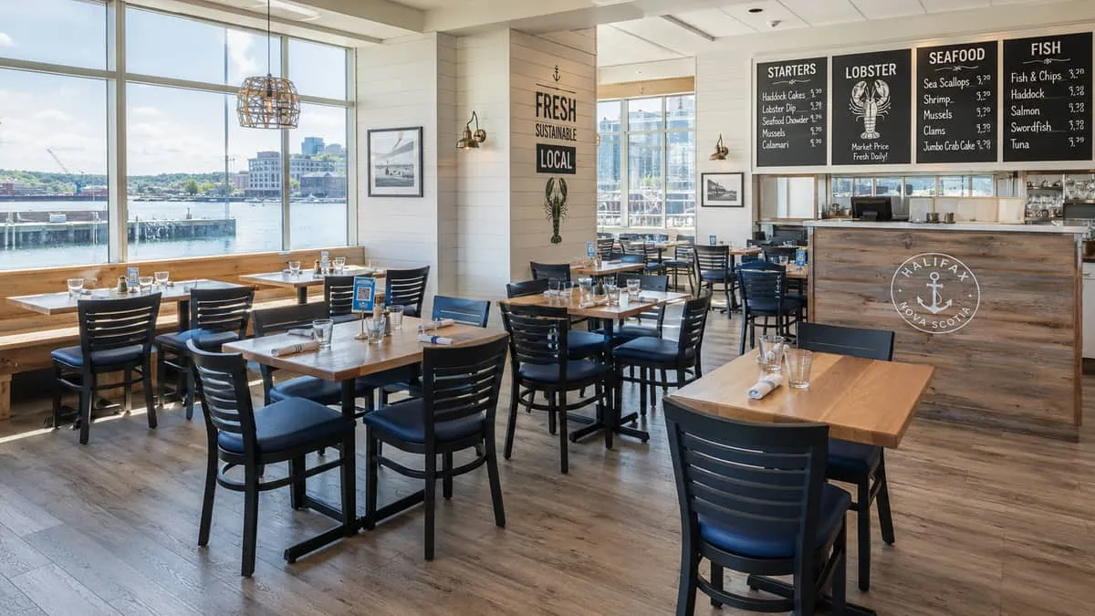 commercial dining chairs and tables set up in a Halifax restaurant with lobster or seafood menu boards visible in the ba