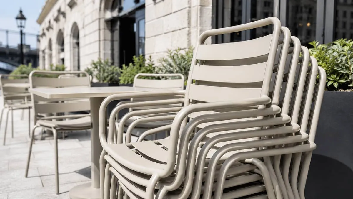 close-up of powder-coated aluminum stacking chairs in a warm neutral finish on a Montreal restaurant terrace, showing cl
