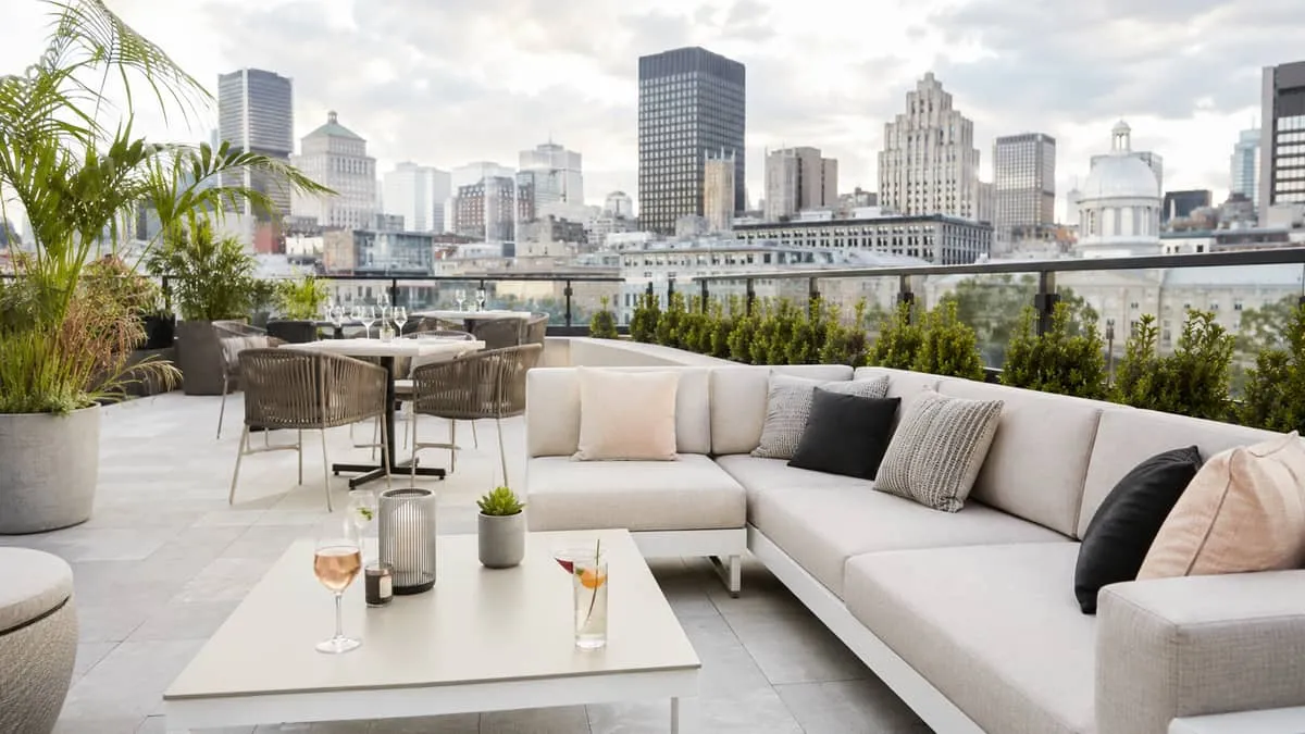Sunbrella cushion seating on a boutique hotel rooftop patio in Montreal, showing a sectional lounge setup with city skyl