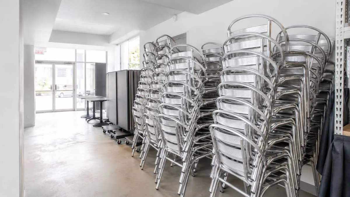 neatly stacked aluminum restaurant chairs in a Montreal restaurant storage area during off-season, showing the practical