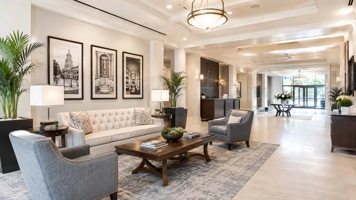 a hotel lobby lounge area with contract-grade furniture including a tufted sofa, armchairs, and a solid wood coffee tabl