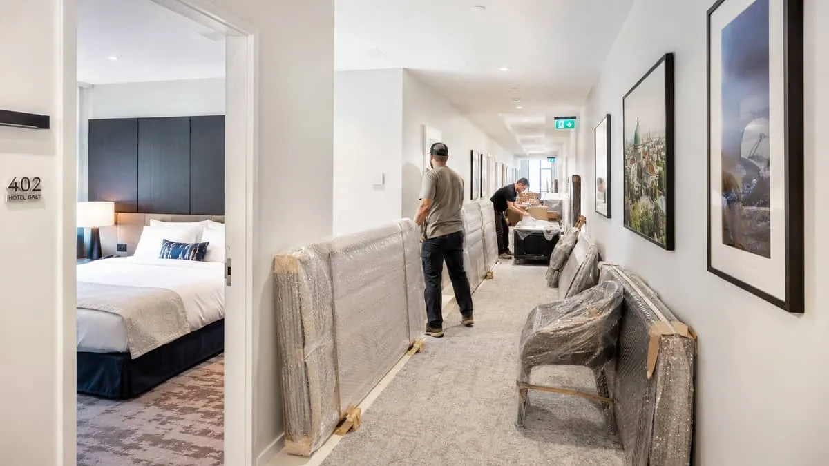 hotel corridor in a Montreal boutique property showing new furniture being installed while adjacent rooms remain in oper