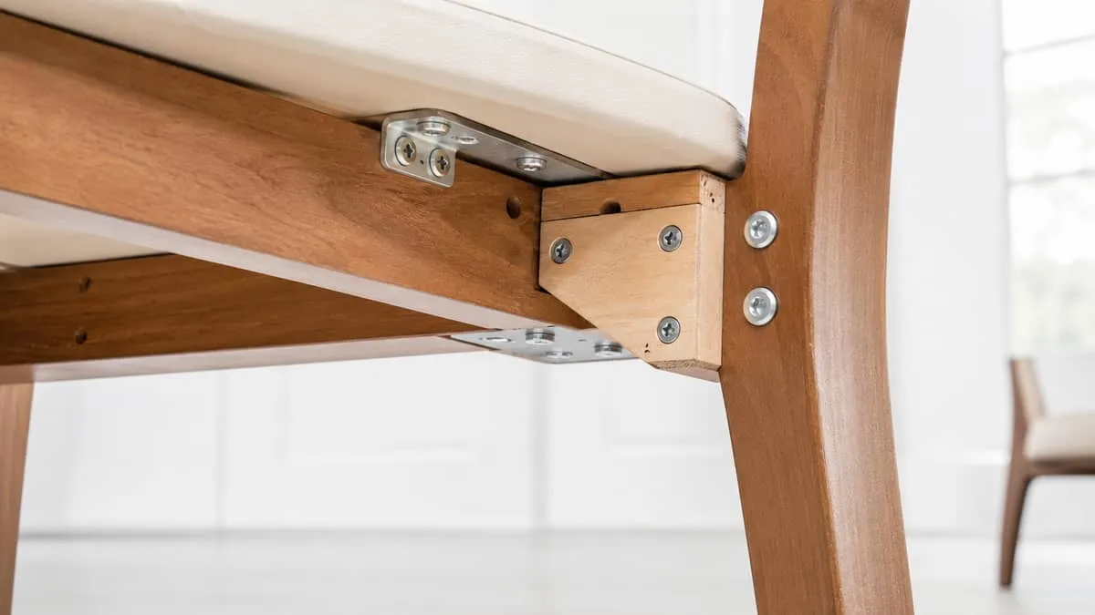 close-up of contract-grade chair joinery showing reinforced corner blocks and steel hardware on a wood frame restaurant 