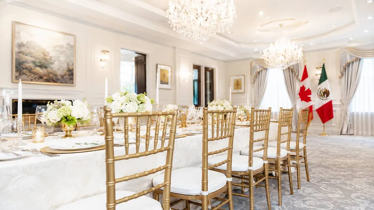 row of gold chiavari chairs with white cushions set at a formally draped banquet table in an Ottawa event venue, soft ch