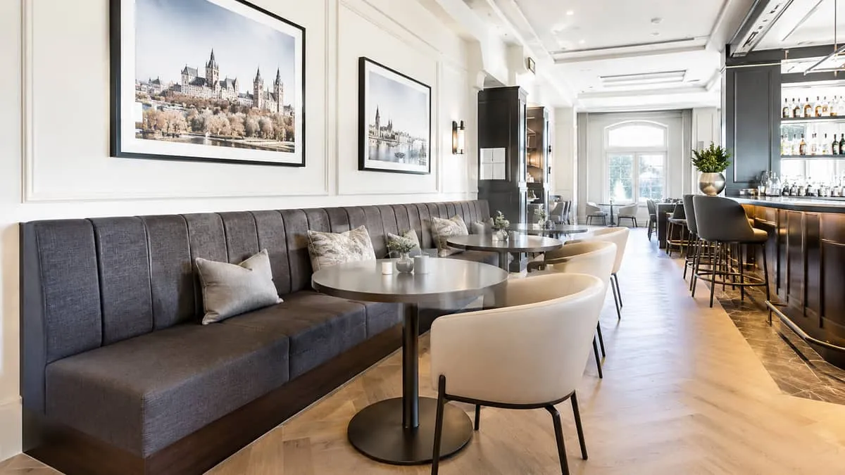 upholstered banquette seating along a wall in a dim-lit lounge setting, showing tight fabric upholstery and solid wood b