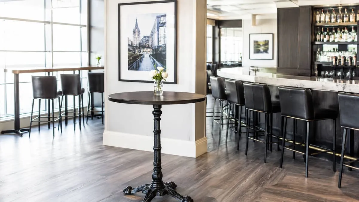 round high-top table with cast-iron pedestal base in a standing-room bar area, with commercial barstools visible in the 