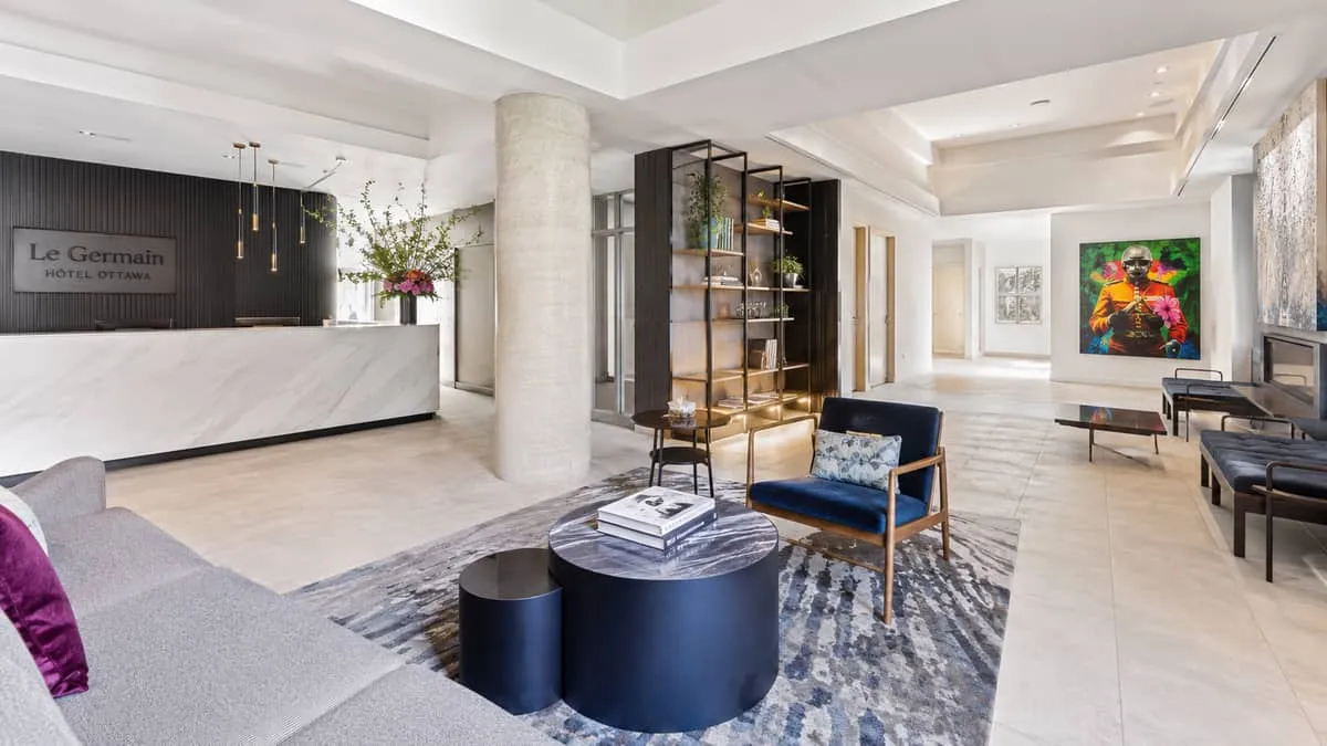 a boutique hotel lobby in Ottawa with a mix of custom upholstered seating, local art on the walls, and warm pendant ligh