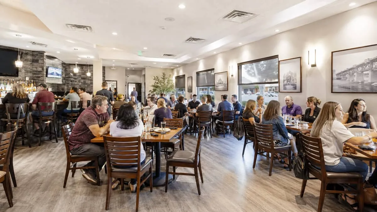a busy mid-range Saskatoon restaurant on Broadway Avenue, showing a full dining room with matching contract chairs and w