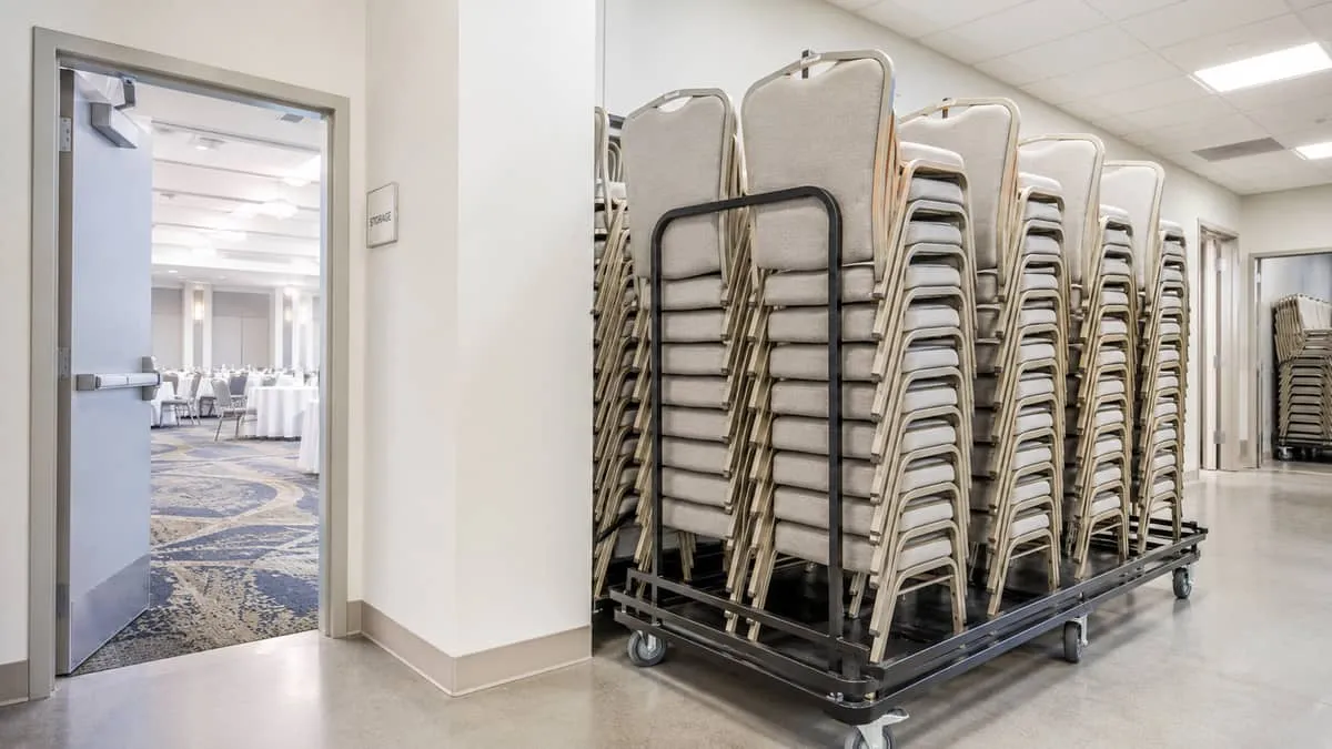 stacked banquet chairs on a trolley inside a hotel storage room, showing how the chairs nest cleanly for efficient stora
