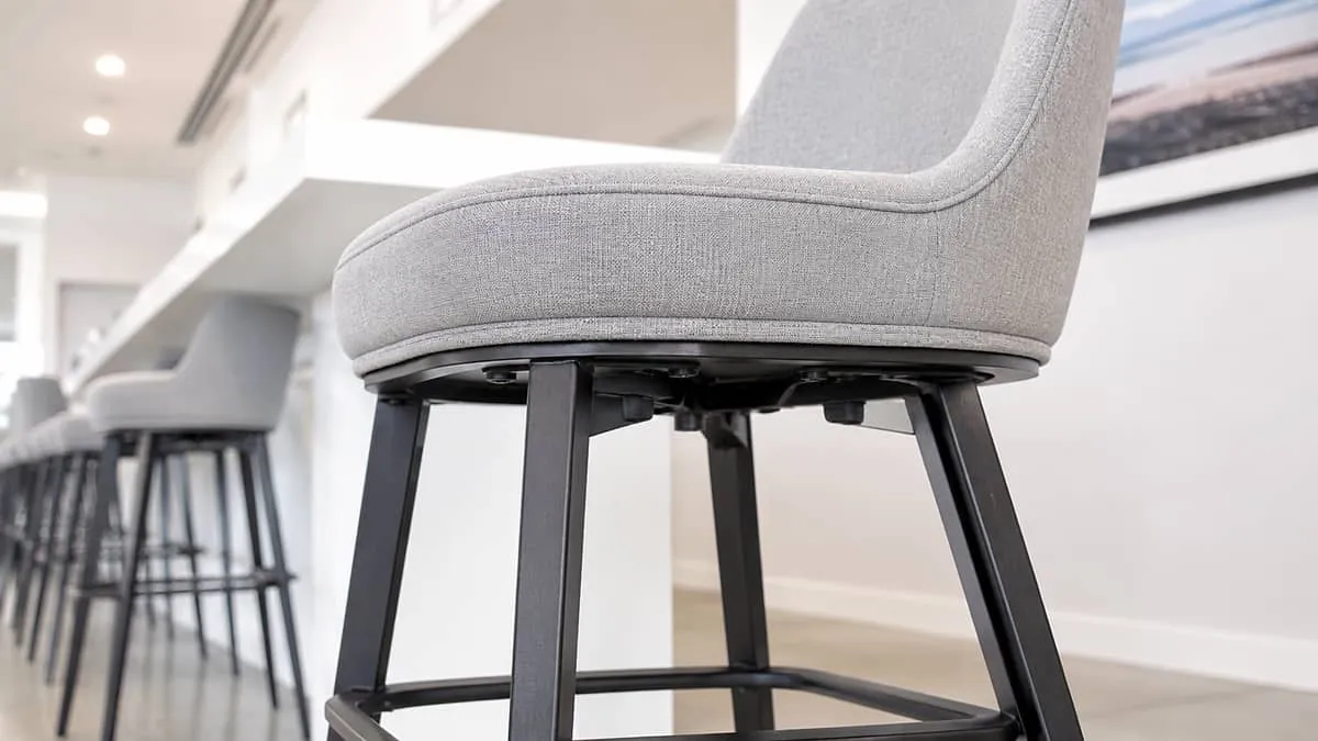close-up of a commercial-grade upholstered barstool showing reinforced base and durable fabric detail, studio or venue s