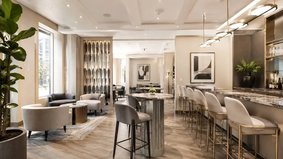 stylish Toronto-style lounge area with curved chairs and mixed material high-top tables, warm tones, contemporary hospit