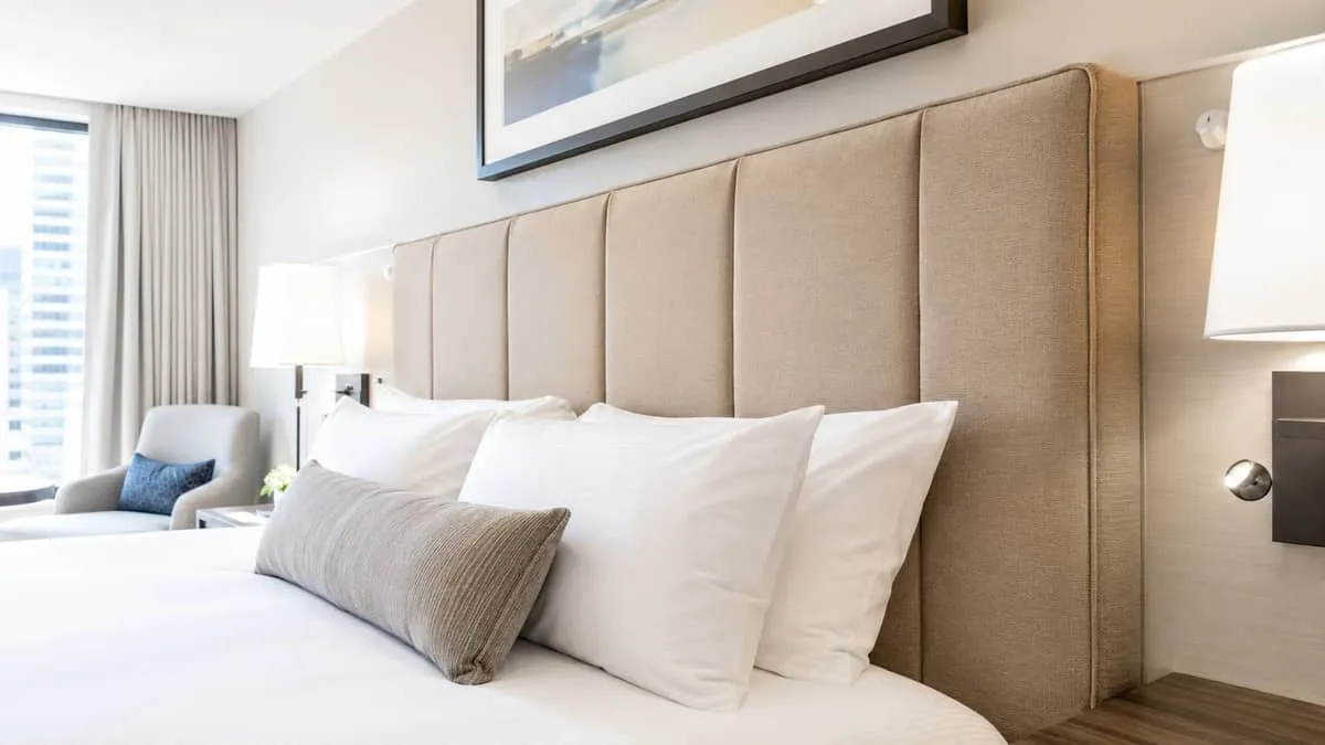 close-up of a contract-grade upholstered headboard with custom fabric in a warm neutral tone, showing quality stitching 