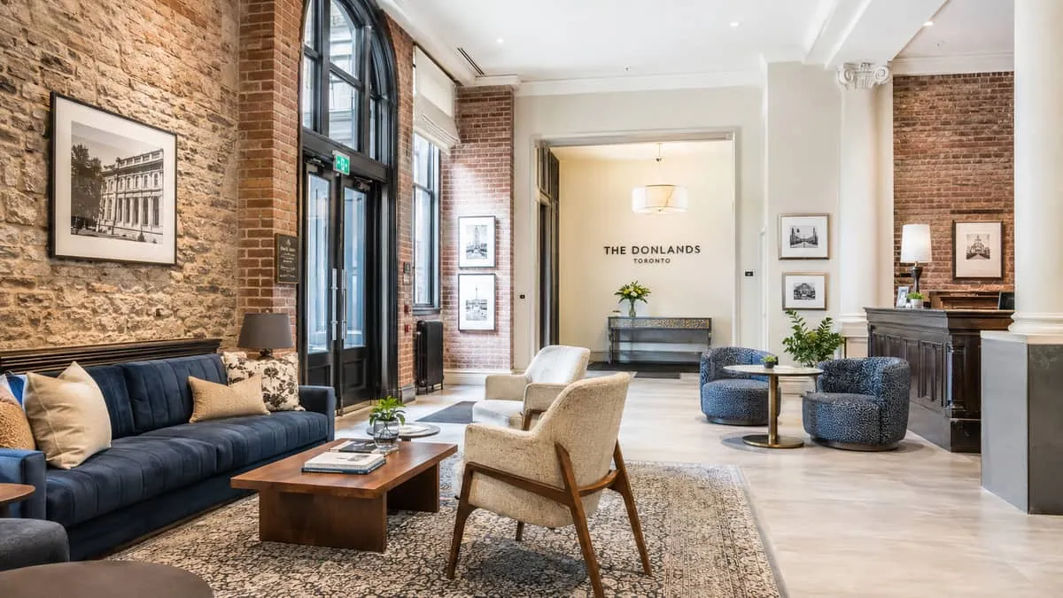 boutique hotel lobby area in a Toronto-style heritage building with exposed brick, showing a mix of custom upholstered s