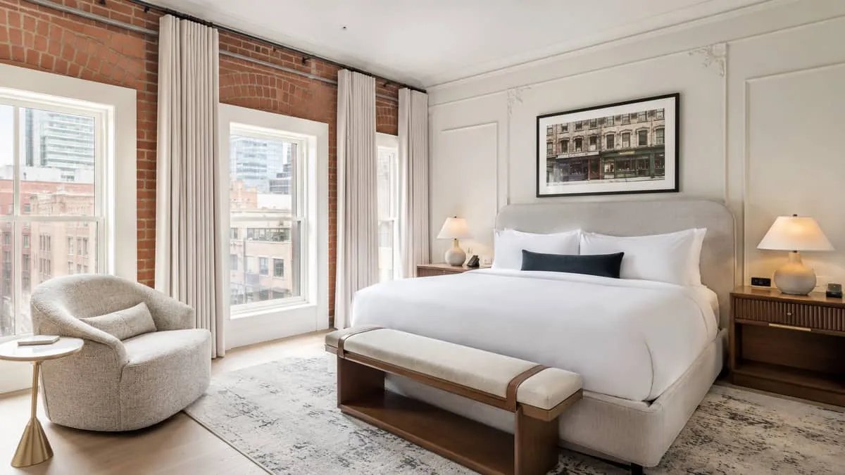 finished boutique hotel guestroom in a Toronto heritage building showing cohesive furniture mix: upholstered headboard, 