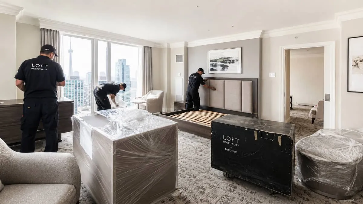 a hospitality furniture delivery or installation scene, showing contract furniture pieces being staged or installed in a