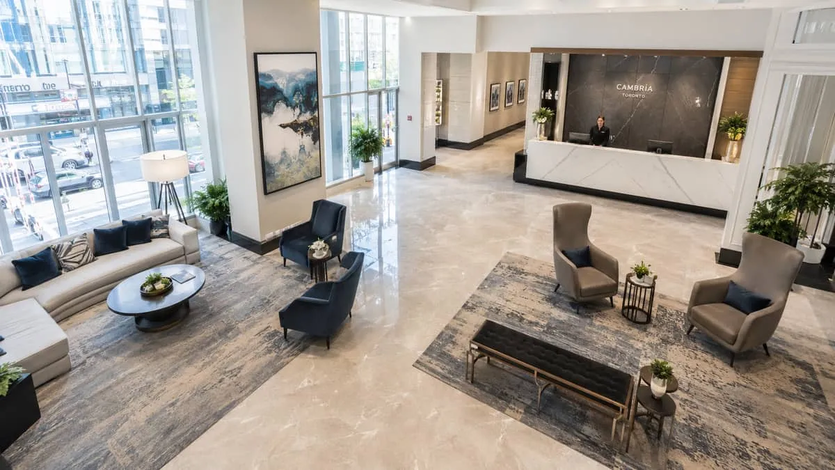 overhead or wide shot of a hotel lobby seating arrangement showing multiple zones: a lounge cluster with low sofas near 