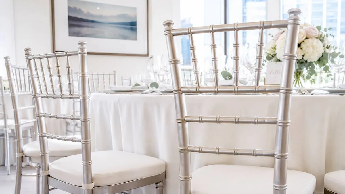 close-up of chiavari banquet chairs arranged at a round table set for a wedding, showing the chair frame detail and upho