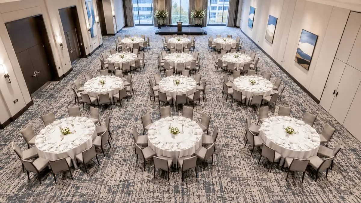 overhead shot of round banquet tables set up in a ballroom grid pattern, 60-inch rounds with chairs, showing the full ro