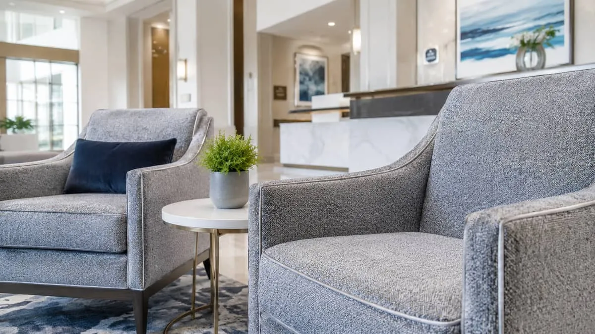 close-up of contract-grade lounge chairs in a hotel lobby with visible quality stitching and durable upholstery fabric, 