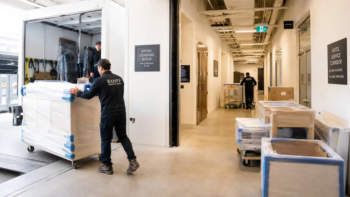 a commercial furniture delivery being coordinated at a Vancouver hotel loading dock, with case goods wrapped in protecti
