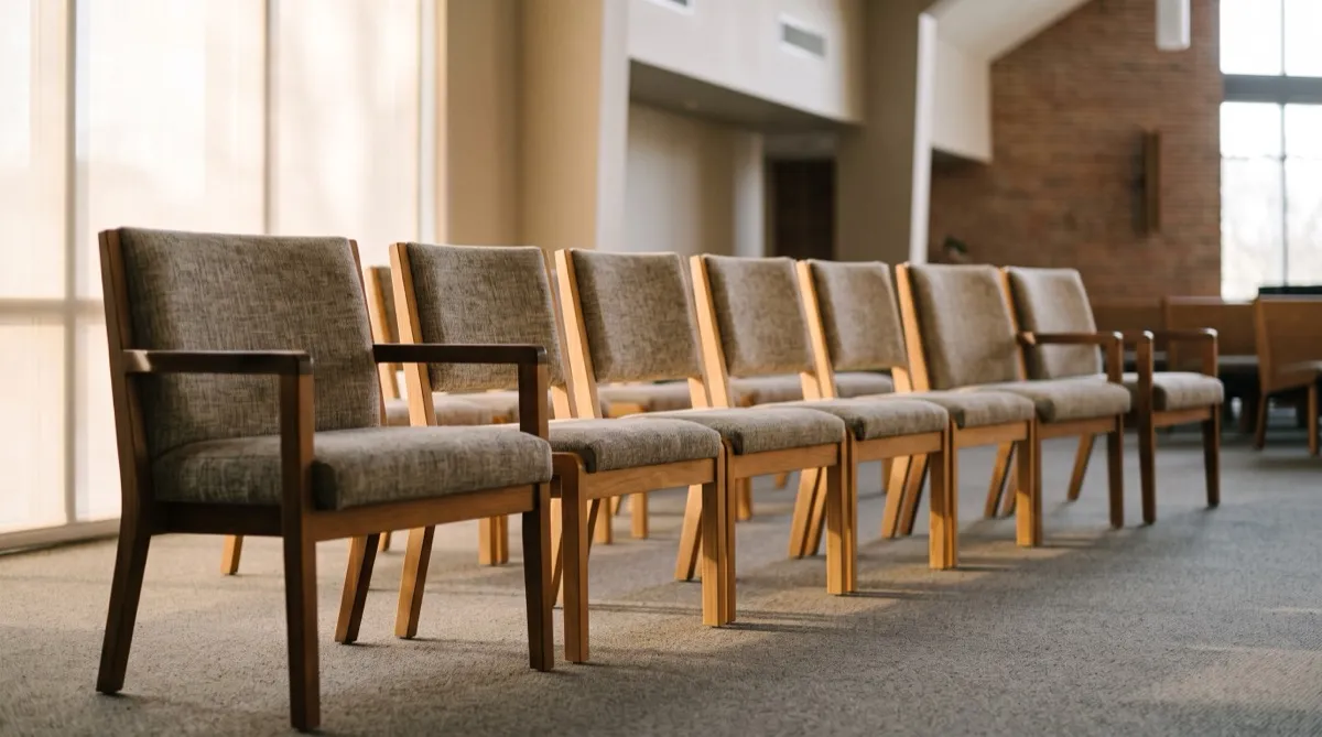 a sanctuary row where the two aisle end chairs have armrests and the middle chairs are armless for tighter spacing, warm side light tracing 
