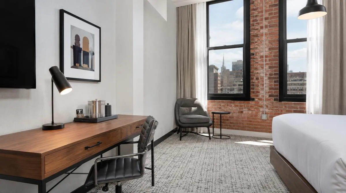 Little Rock boutique hotel guestroom near the Capitol showing cohesive design palette with matching frame finishes and tonal upholstery